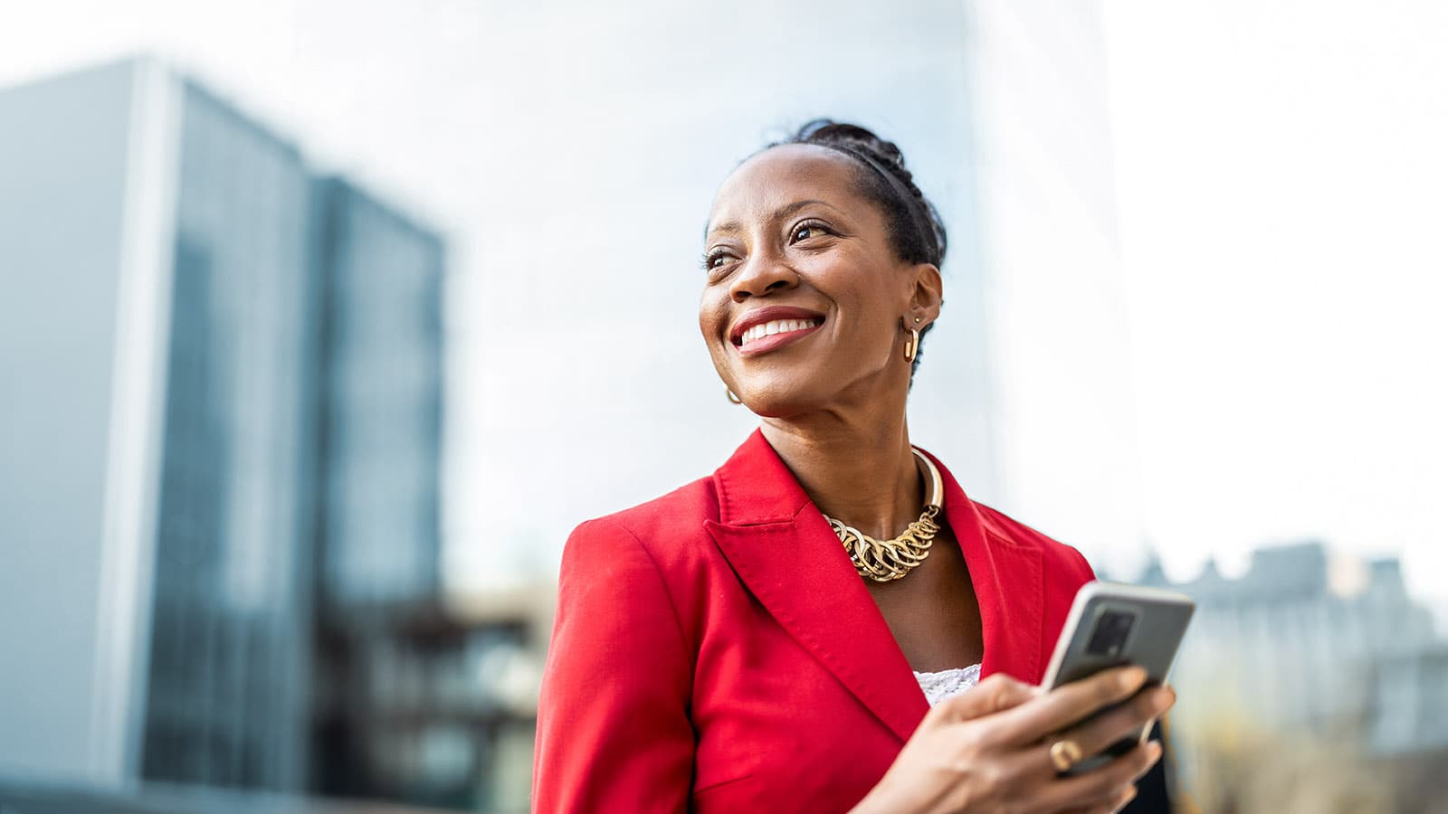 Portrait of smiling mature businesswoman using mobile phone in urban setting.