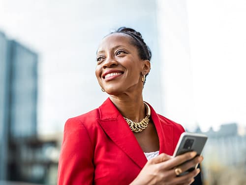 Portrait of smiling mature businesswoman using mobile phone in urban setting.