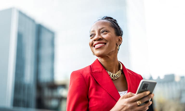 Portrait of smiling mature businesswoman using mobile phone in urban setting.