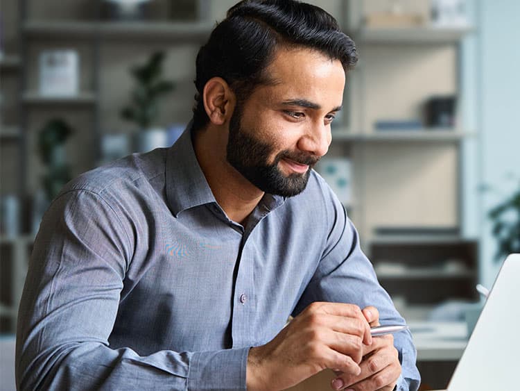 Young Indian businessman working on laptop in home office.